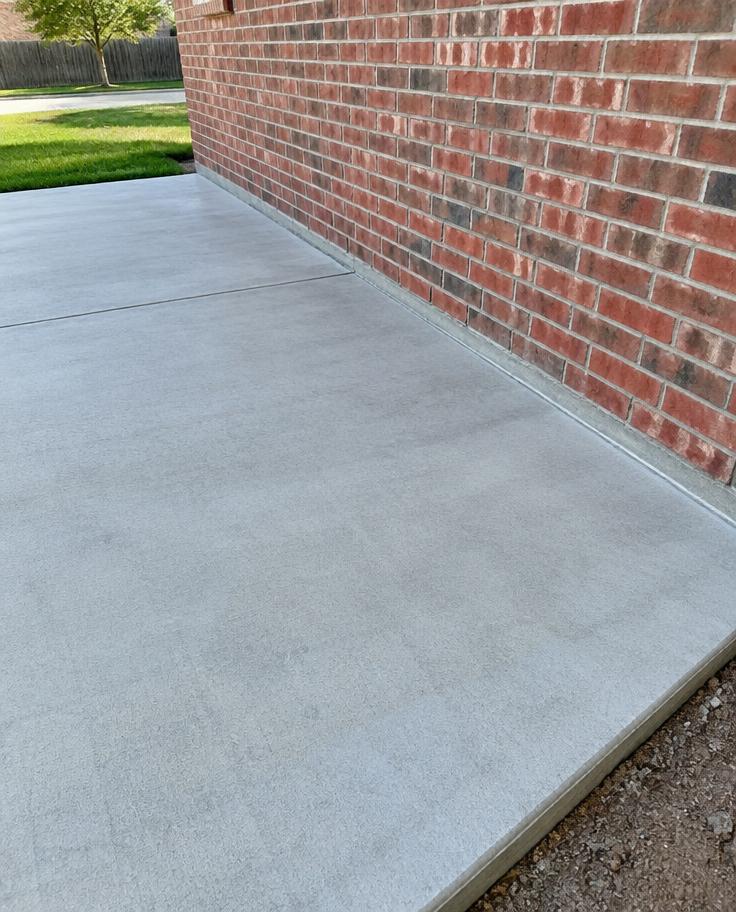 Smooth concrete flatwork beside a brick wall